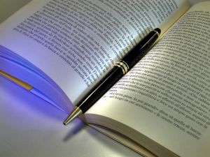 otwarta książka na której leży długopis