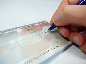 ręka człowieka w trakcie podpisywania czeku